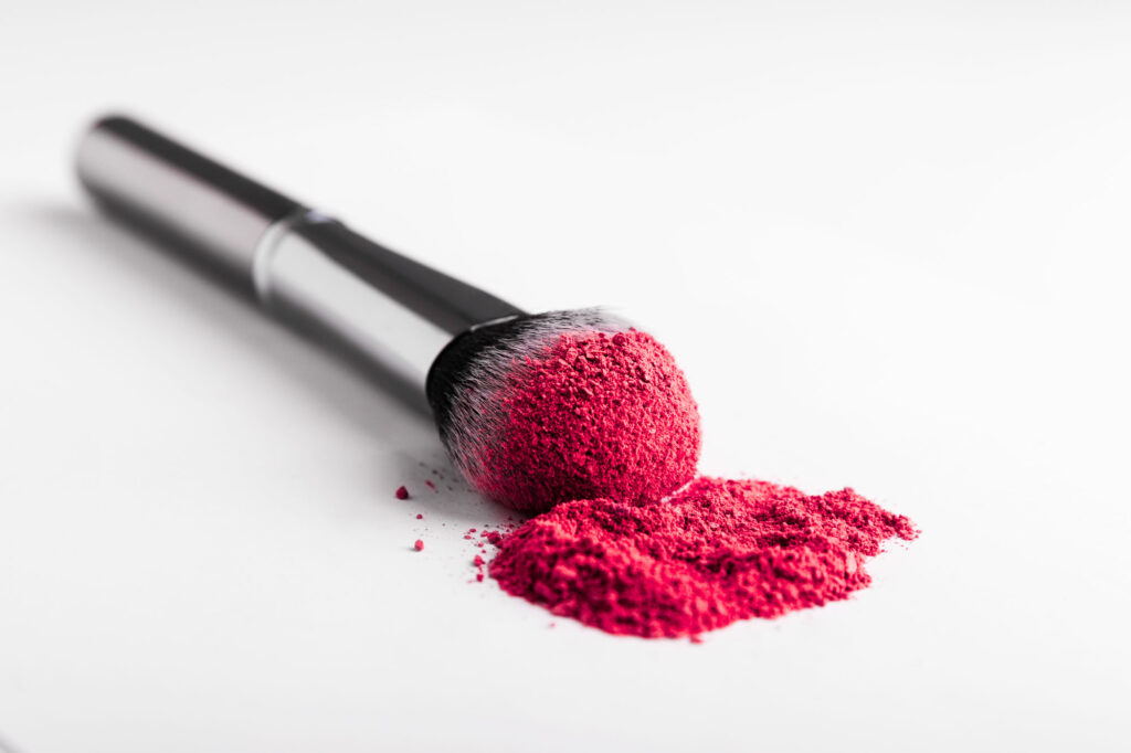 Cosmetic brush with old pink powder on white table