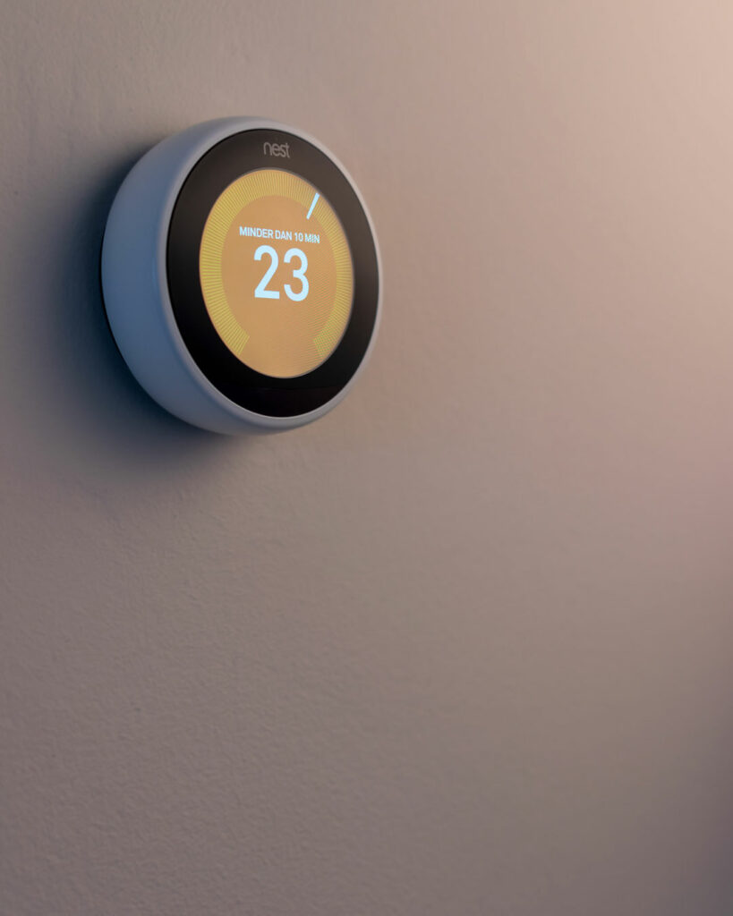 Close up of the Nest Thermostat with orange background