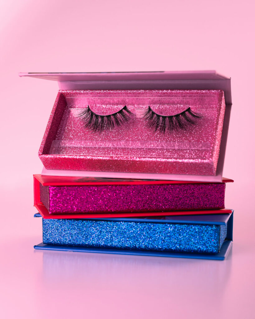 3 eye lashes boxes on a pink background