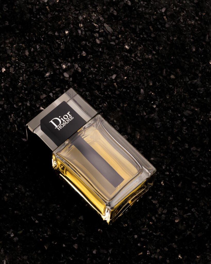 Christian Dior Homme parfum lying on black small stones